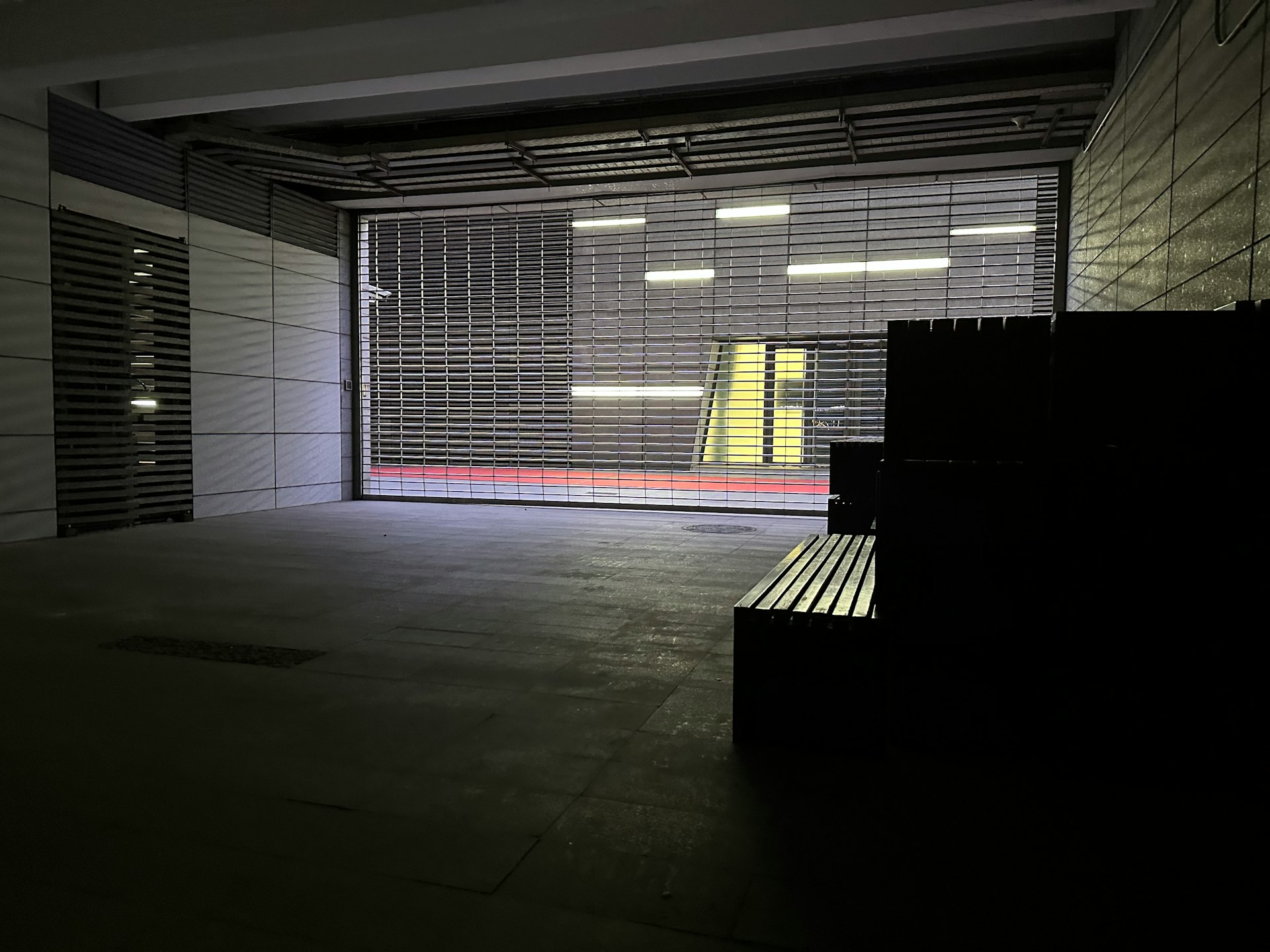 an empty parking garage with a bench in front of it, instalaciones, almacenamiento